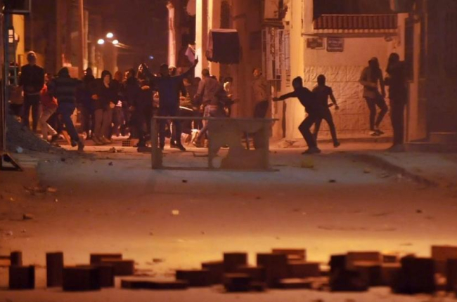Manifestantes lanzan piedras contra las fuerzas de seguridad en el distrito de Djebel Lahmer, en Túnez, el 10 de enero.-/ AFP / SOFIENE HAMDAOUI