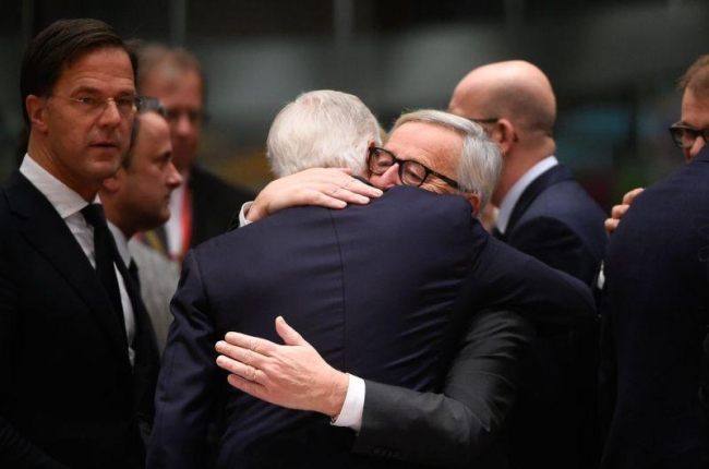 Juncker abraza a Barnier (de espaldas), a su llegada a la cumbre del Consejo Europeo, este domingo en Bruselas.-AFP