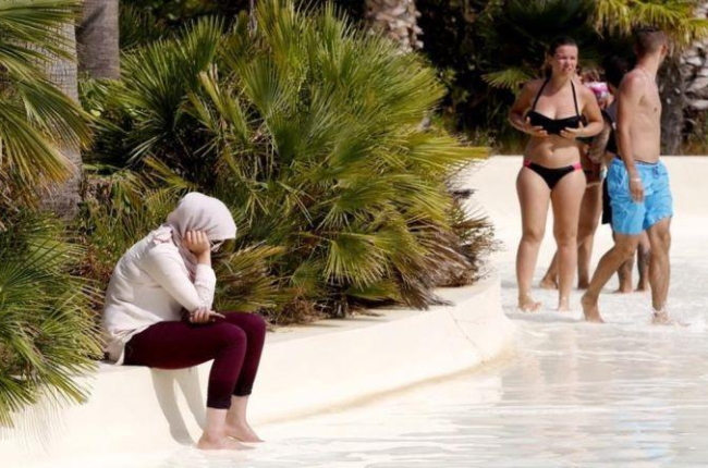 Una mujer musulmana se refresca los pies en el Aquaparc de Roses, donde está prohibido el 'burkini' por razones de seguridad.-JOAN CASTRO ICONNA