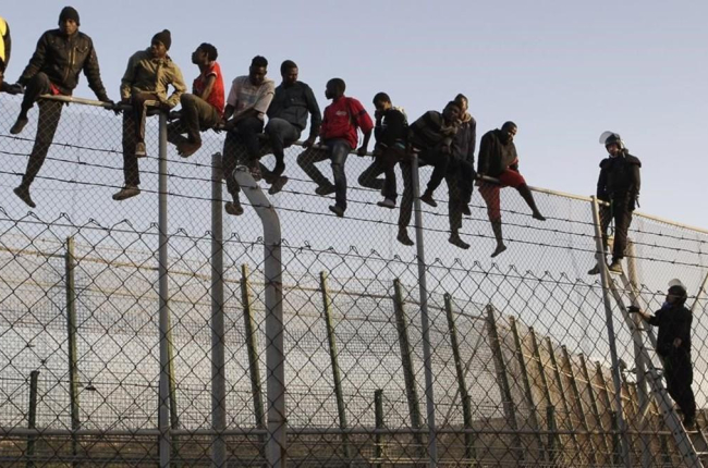 Policías españoles tratan de disuadir a inmigrantes encaramados a la valla de Melilla, fronteriza con Marruecos. /-EFE / ARCHIVO