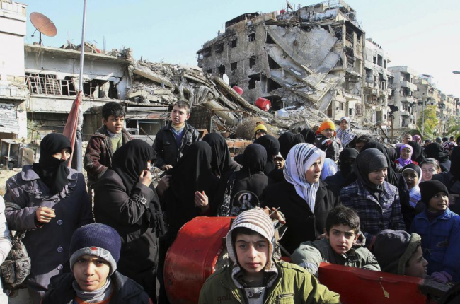 Decenas de sirios hacen cola para recibir comida en las afueras de Damasco.-AP