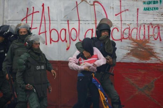 Guardias bolivarianos detienen a un manifestante durante una protesta en Caracas.-/ REUTERS / CARLOS GARCÍA RAWLINS
