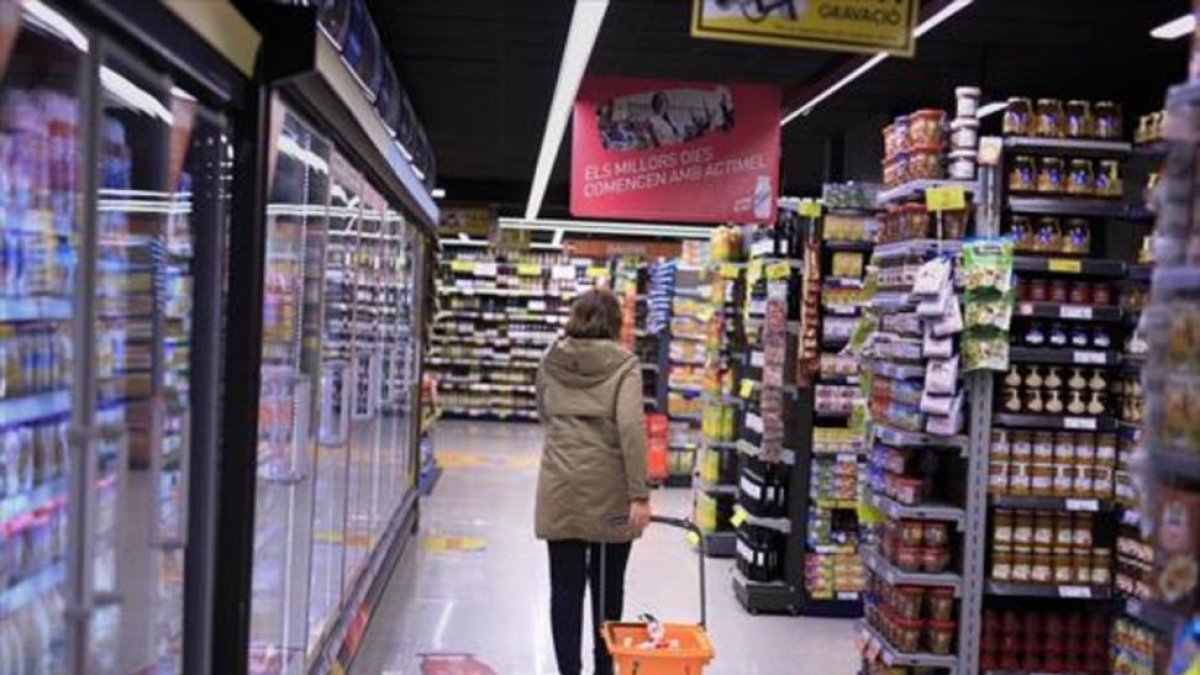 Una clienta deambula entre los estantes llenos de productos de un supermercado .-EL PERIÓDICO