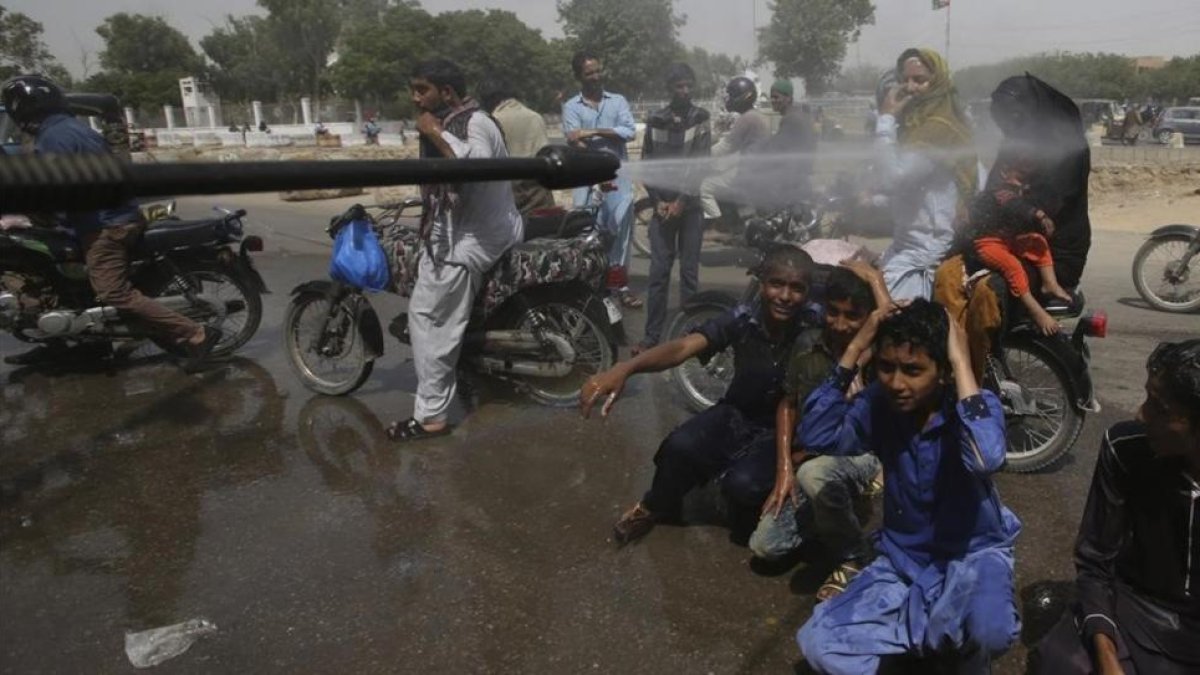 Voluntarios pulverizan a la gente en Karachi.-FAREED KHAN