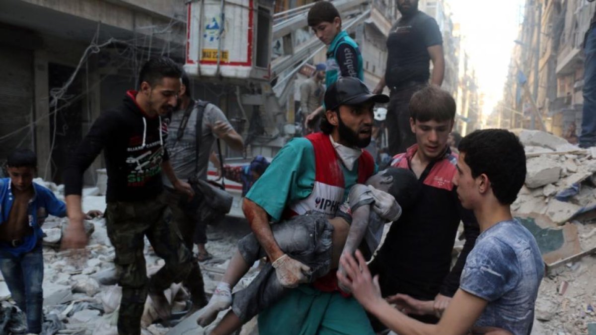Un hombre saca el cadáver de un niño de una casa alcanzada por un bombardeo en Alepo.-AMEER ALHALBI / AFP