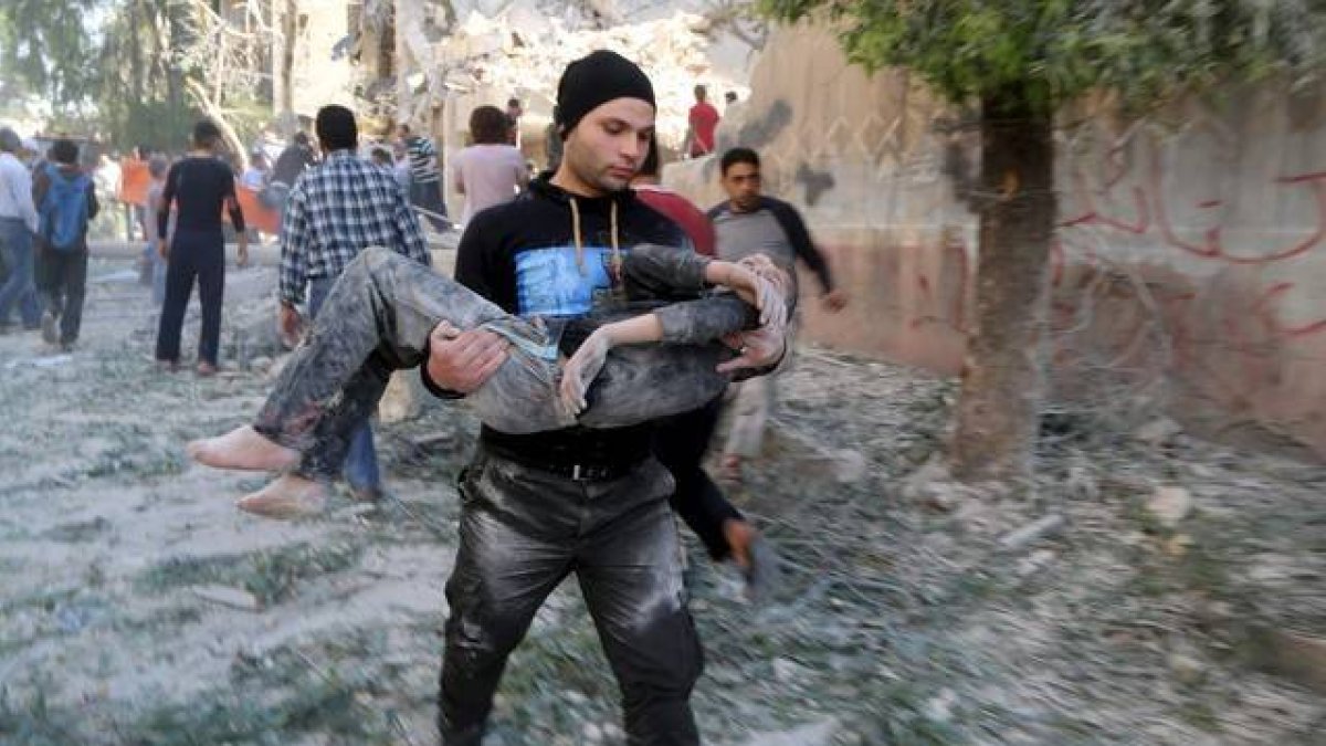 Un hombre traslada a un niño herido en el bombardeo sobre una escuela en Alepo.-Foto: REUTERS/ HOSAM KATAN