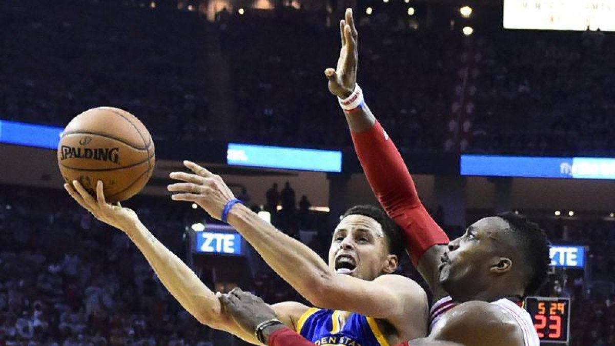 Stephen Curry entra a canasta bajo la presión de Dwight Howard.-Foto: EFE