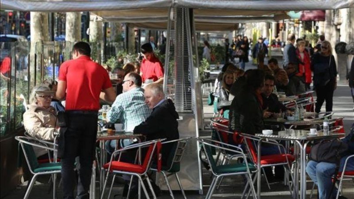 Un camarero atiende a clientes en una terraza. Es el colectivo con más contratos temporales.-DANNY CAMINAL