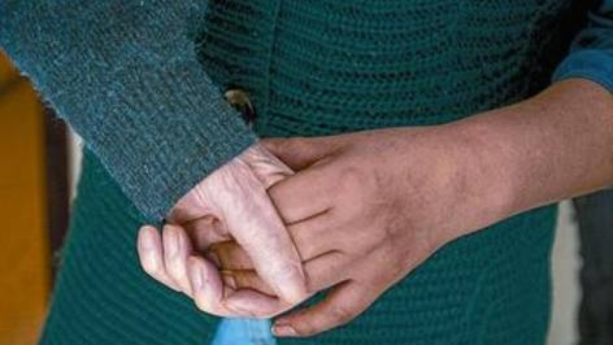Un anciano con alzhéimer coge la mano de la persona que lo asiste.-Foto: ARCHIVO / FERRAN NADEU