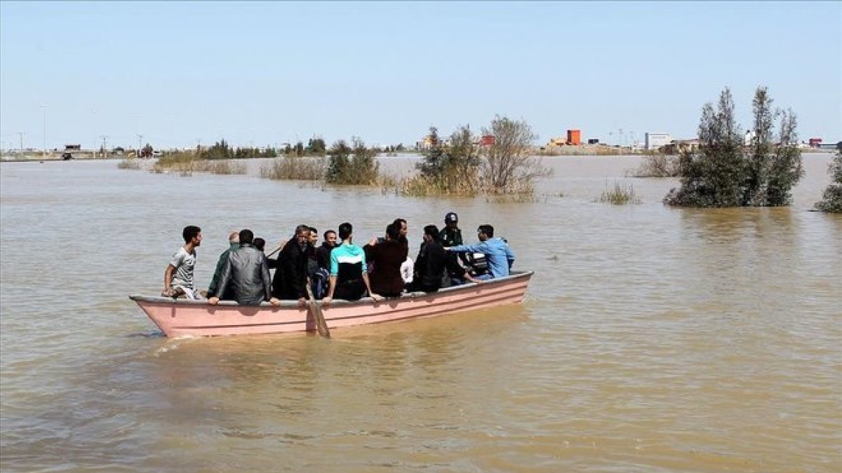 Iranís de la provincia de Golestan, anegada por las lluvias, en una barcaza a finales de marzo.-REUTERS