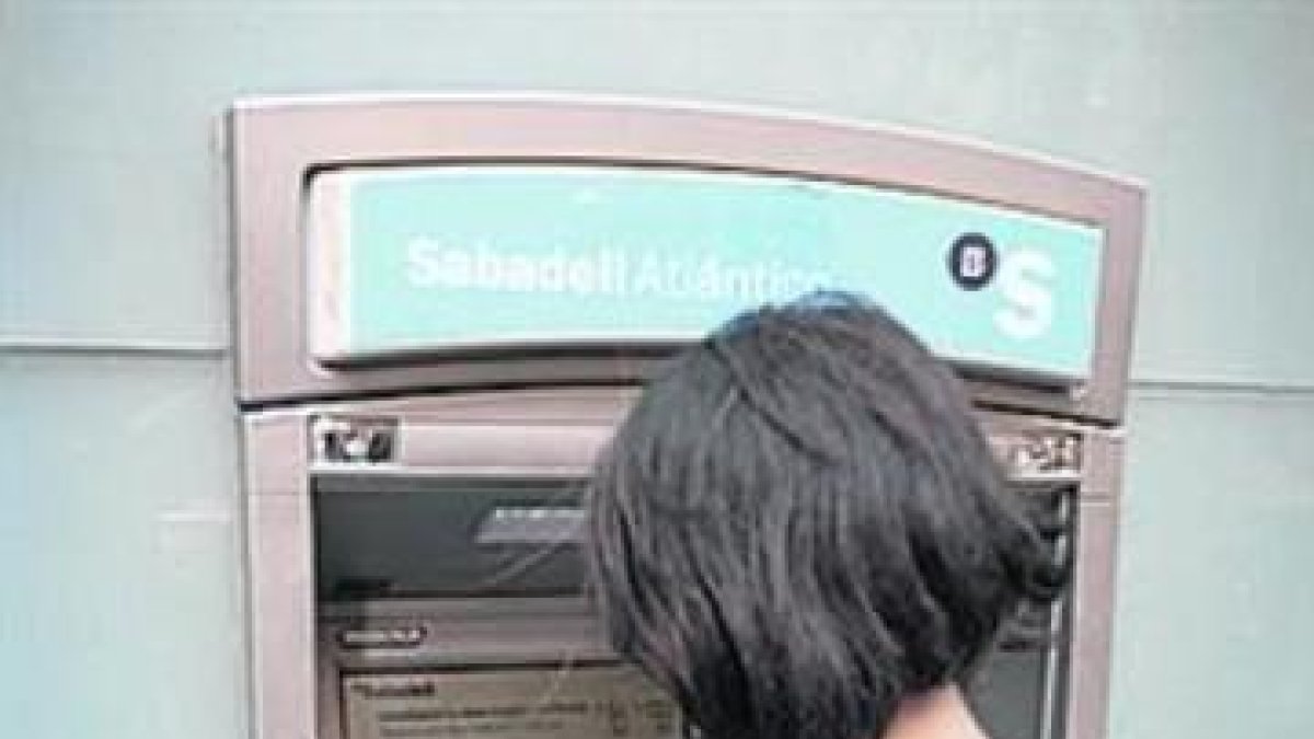 Una usuaria utiliza un cajero.-