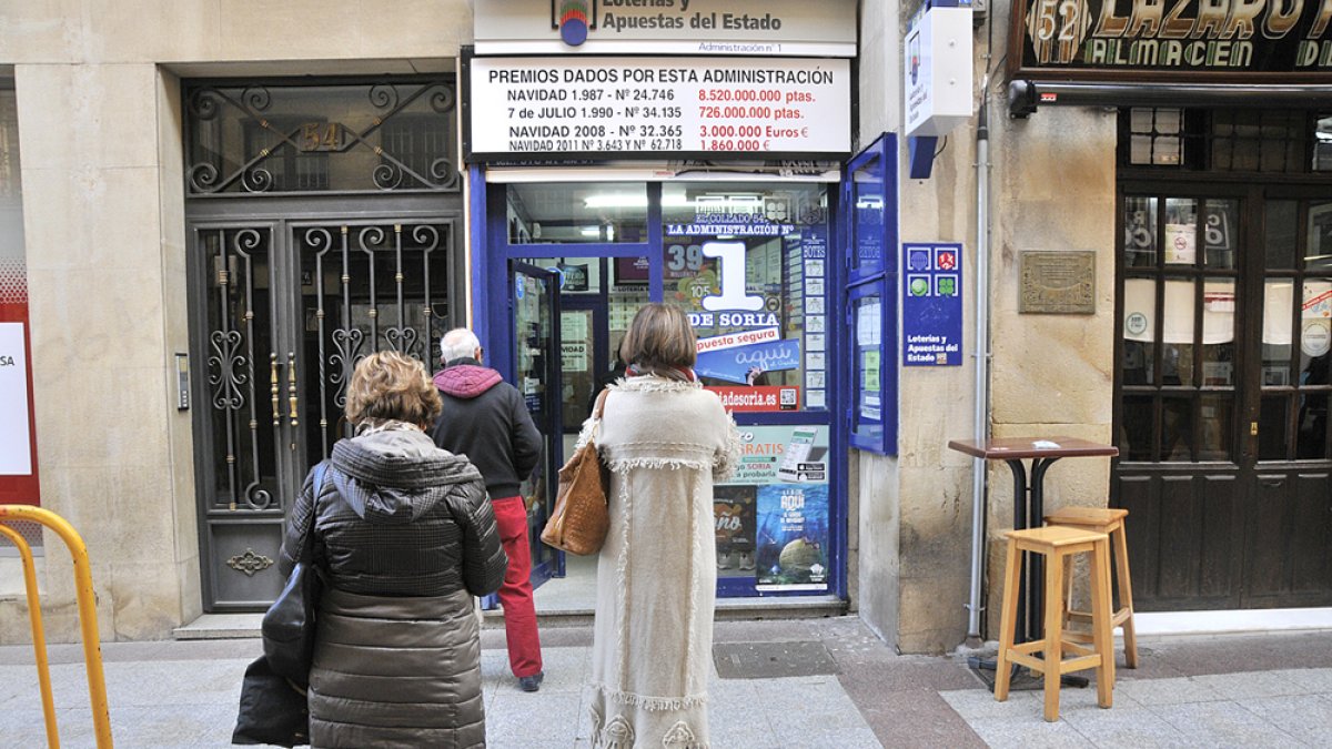 Varias personas hacen cola en una administración de lotería en una foto de archivo.-HDS