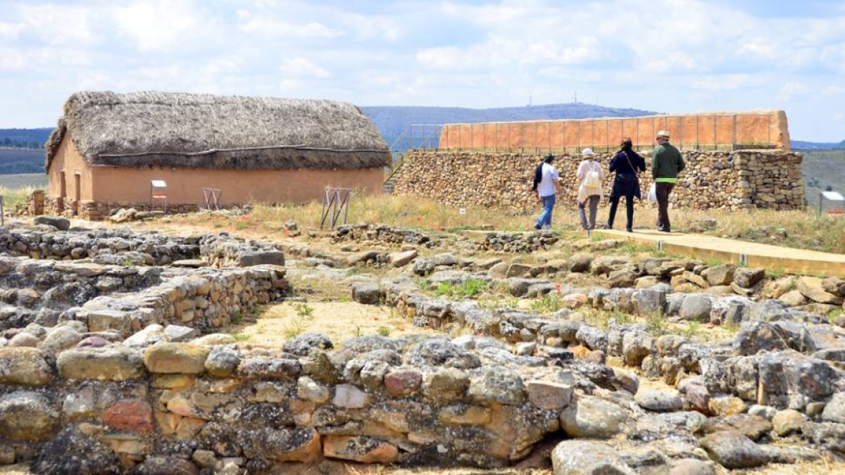 Visitantes en el yacimiento de Numancia junto a una de las viviendas recreadas.-ÁLVARO MARTÍNEZ