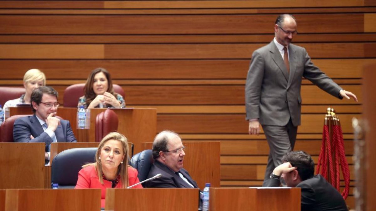 El presidente de la Junta, Juan Vicente Herrera, conversa con el procurador Carlos Fernández Carriedo en el Pleno de las Cortes-ICAL