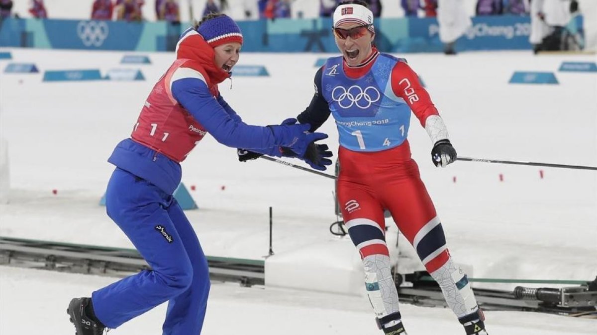 Su compañera Oestberg felicita a Bjoergen nada más cruzar la línea de meta.-EFE