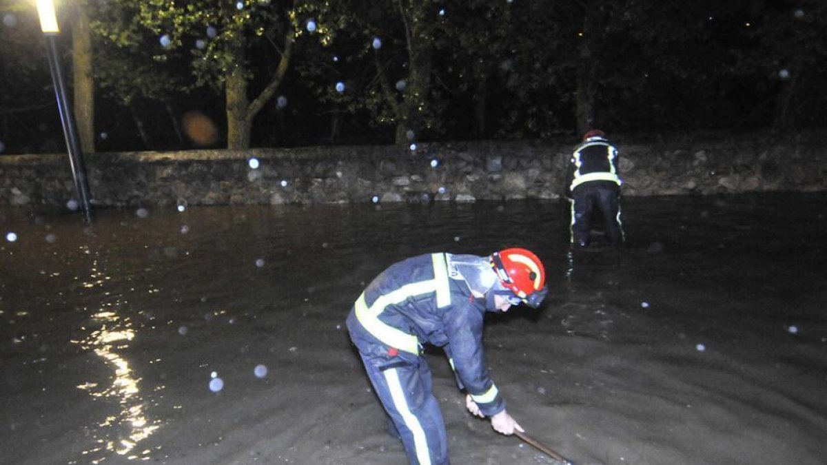 Un bombero trata de abrir un sumidero en San Prudencio en la noche del domingo.-VALENTÍN GUISANDE