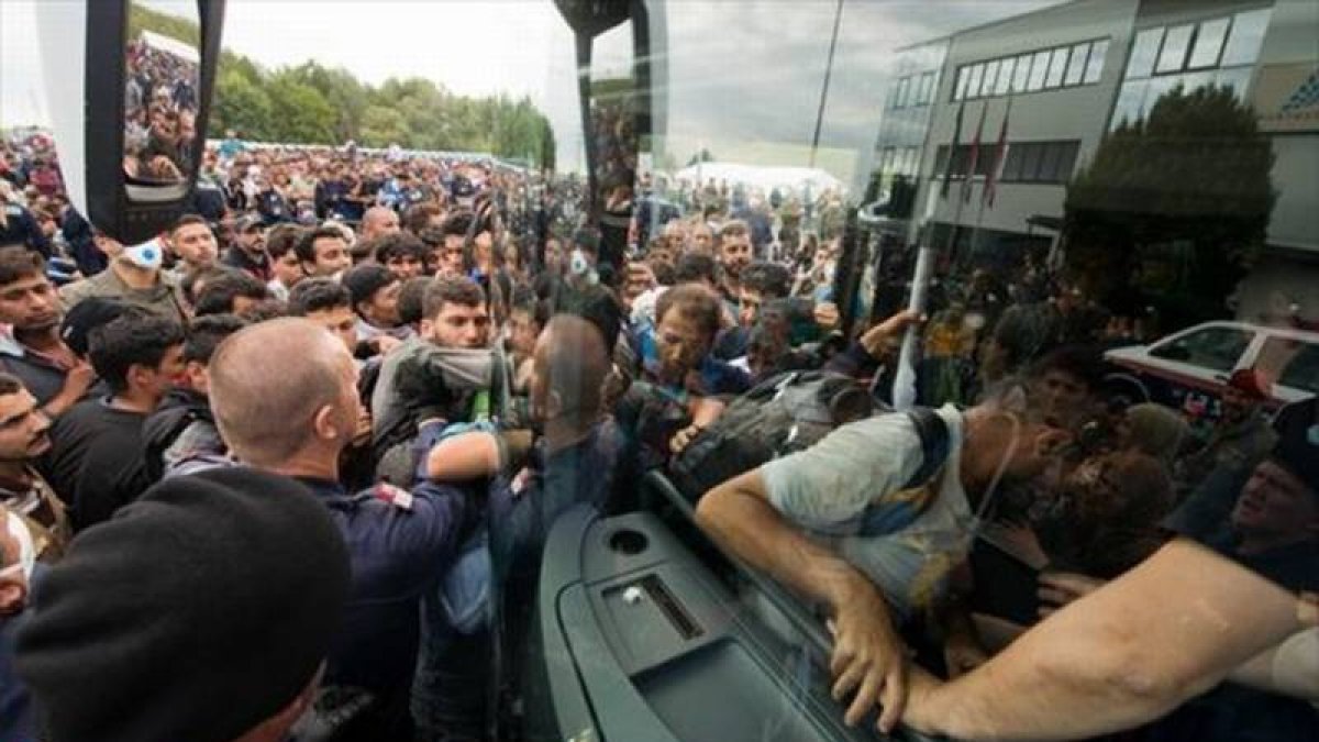 Refugiados suben a un autocar cerca de Heiligenkreuz, en la frontera entre Austria y Hungría, ayer.-AP / CHRISTIAN BRUNA