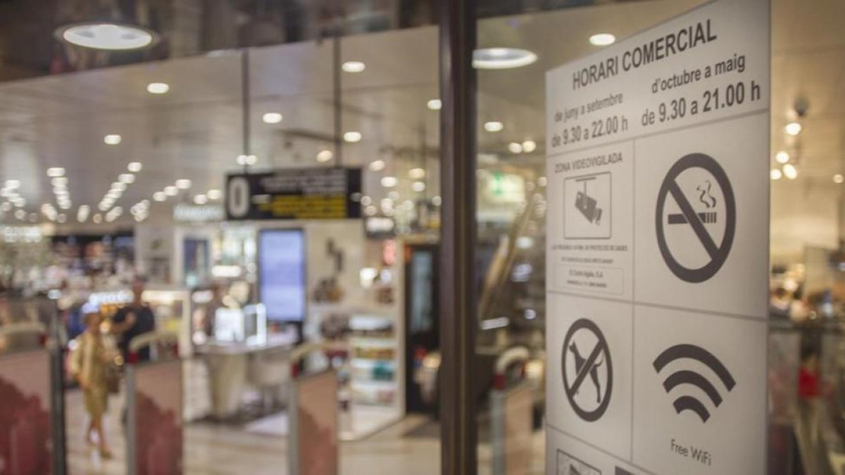 Cartel con el nuevo horario comercial en una tienda de Barcelona.-CARLOS MONTAÑÉS