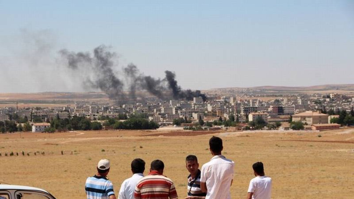 Gente mira el humo de los combates en Kobane desde la frontera turca.-Foto: AFP / STRINGER