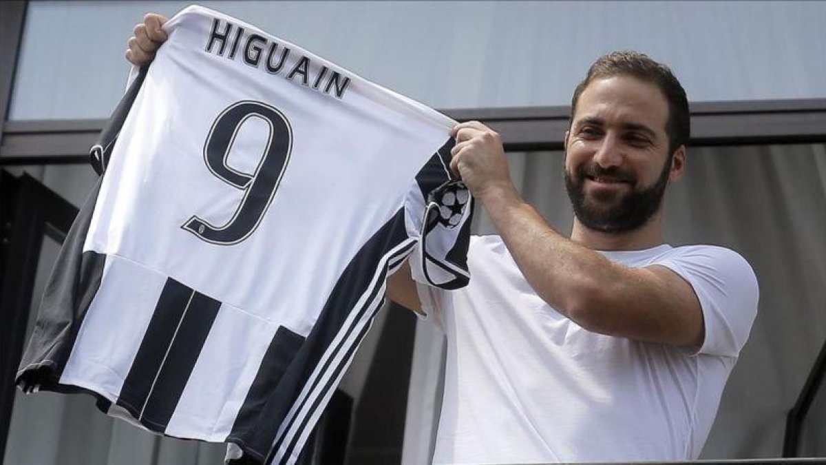 El delantero Gonzalo Higuaín muestra a sus aficionados su nueva camiseta de la Juventus.-MARCO BERTORELLO / AFP