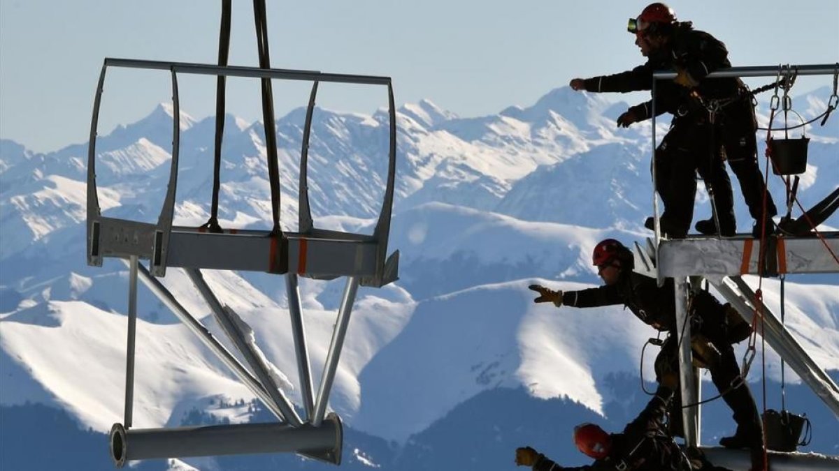 Varios técnicos intentan alcanzar una pieza de la estructura metálica durante la instalación de la plataforma en la cima del Pico de Midi, una de las montañas más altas de Francia, en Bagneres-de-Bigorre, el 30 de enero.-AFP / PASCAL PAVANI