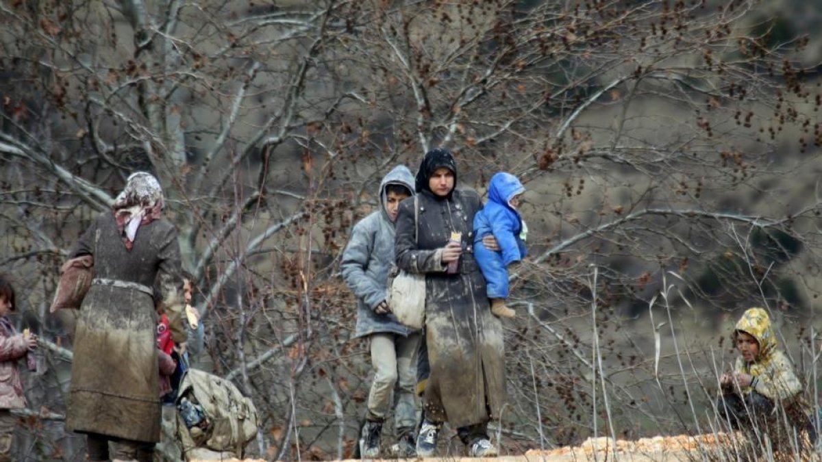 Refugiados sirios, cubiertos de barro, junto a la frontera con Turquía.-REUTERS / AMMAR ABDULLAH
