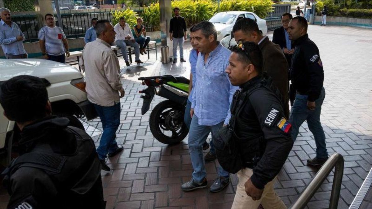 Momento en que funcionarios policiales detienen al exministro venezolano de Interior Miguel Rodriguez Torres, en el centro de la imagen con camisa azul.-EFE / MIGUEL GUTIÉRREZ