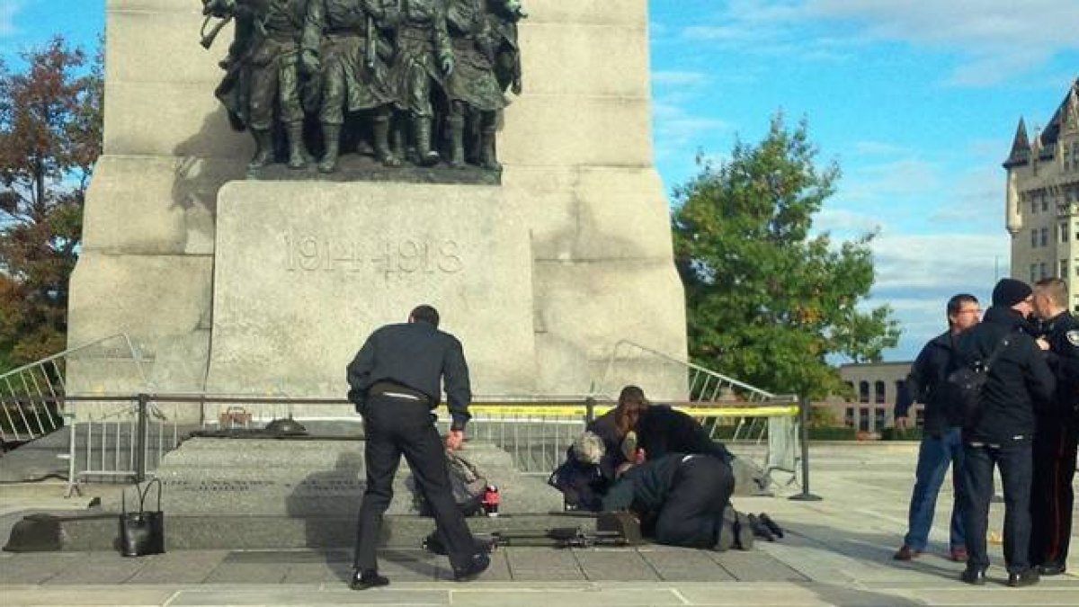 Unos soldados atienden a un compañero herido, ante el monumento de los veteranos de guerra en Ottawa.-