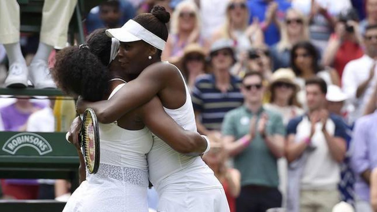 Serena (izquierda) y Venus Williams se abrazan tras el partido de octavos de final de Wimbledon, que ha acabado con victoria de la menor de las hermanas.-REUTERS / TOBY MELVILLE