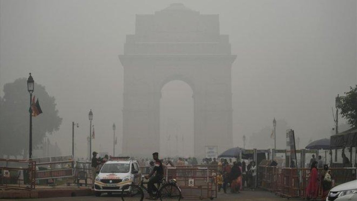 Turistas visitan la Puerta de la India bajo una fuerte niebla de polución en Nueva Deli.-SAJJAD HUSSAIN (AFP)