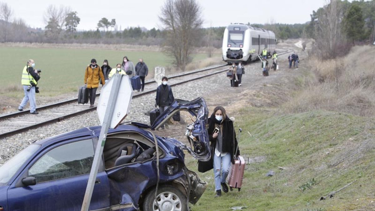 Los pasajeros del tren caminan con sus maletas junto al automóvil siniestrado. LUIS ÁNGEL TEJEDOR