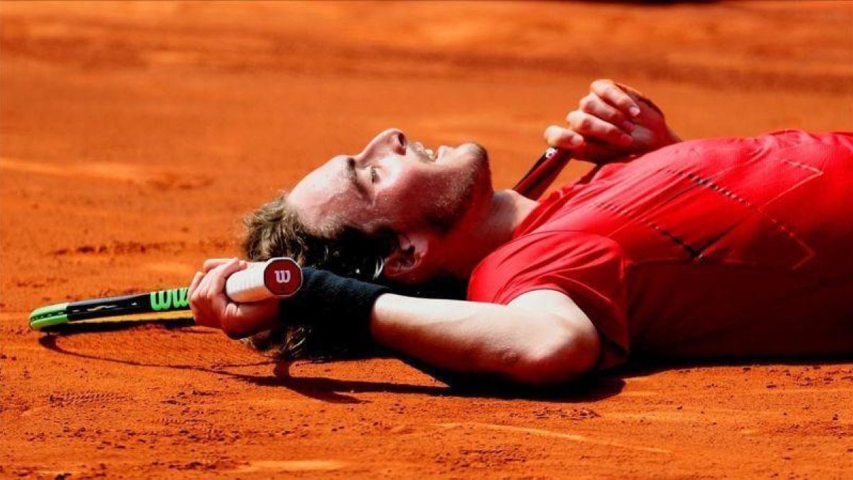Tsitsipas, tendido en la tierra tras batir a Carreño este sábado.-EFE / ALEJANDRO GARCÍA
