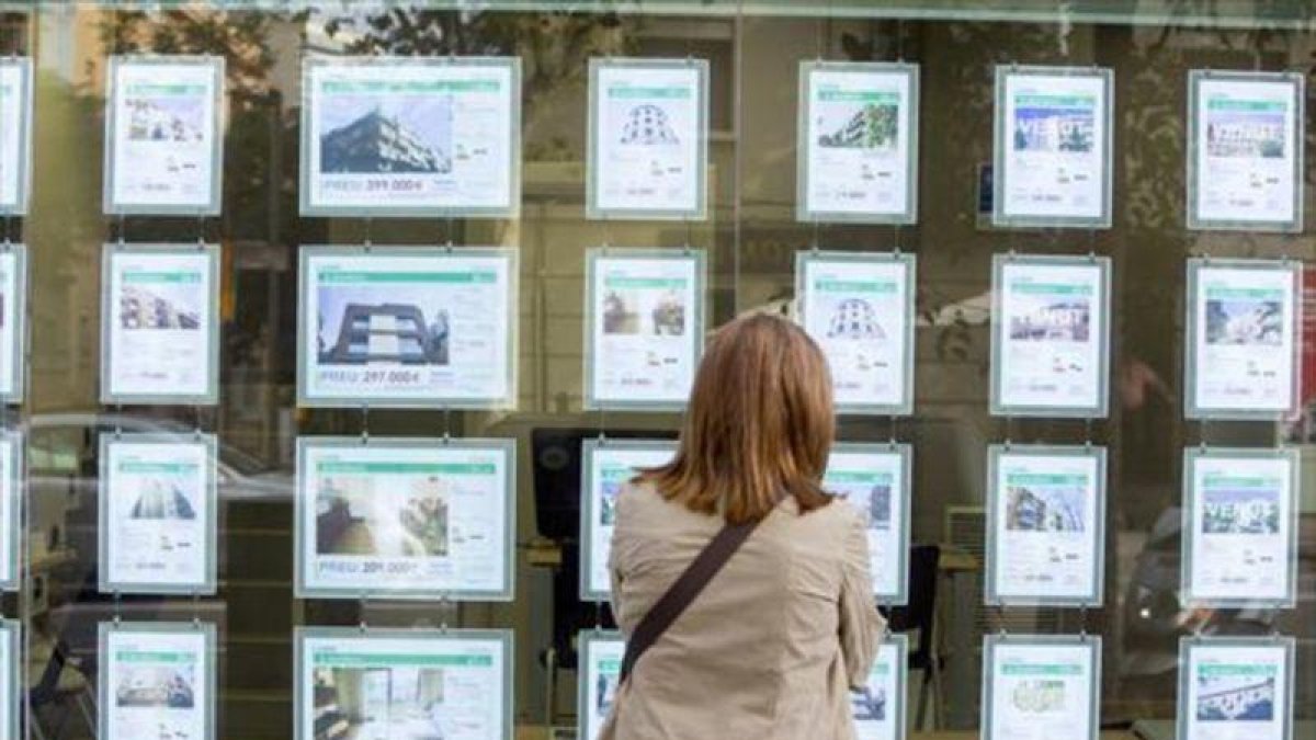 Una mujer mira ofertas de compra y alquiler de viviendas.-EL PERIÓDICO