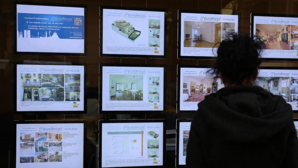 Ofertas de ventas de pisos en el escaparate de una inmobiliaria-/ RICARD CUGAT