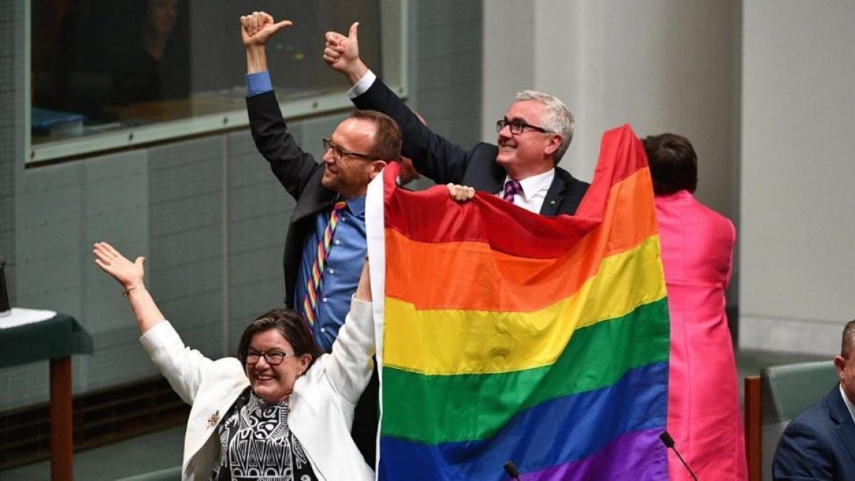 Tres diputados agitan la bandera arcoiris tras la aprobación de la ley.-MICK TSIKAS