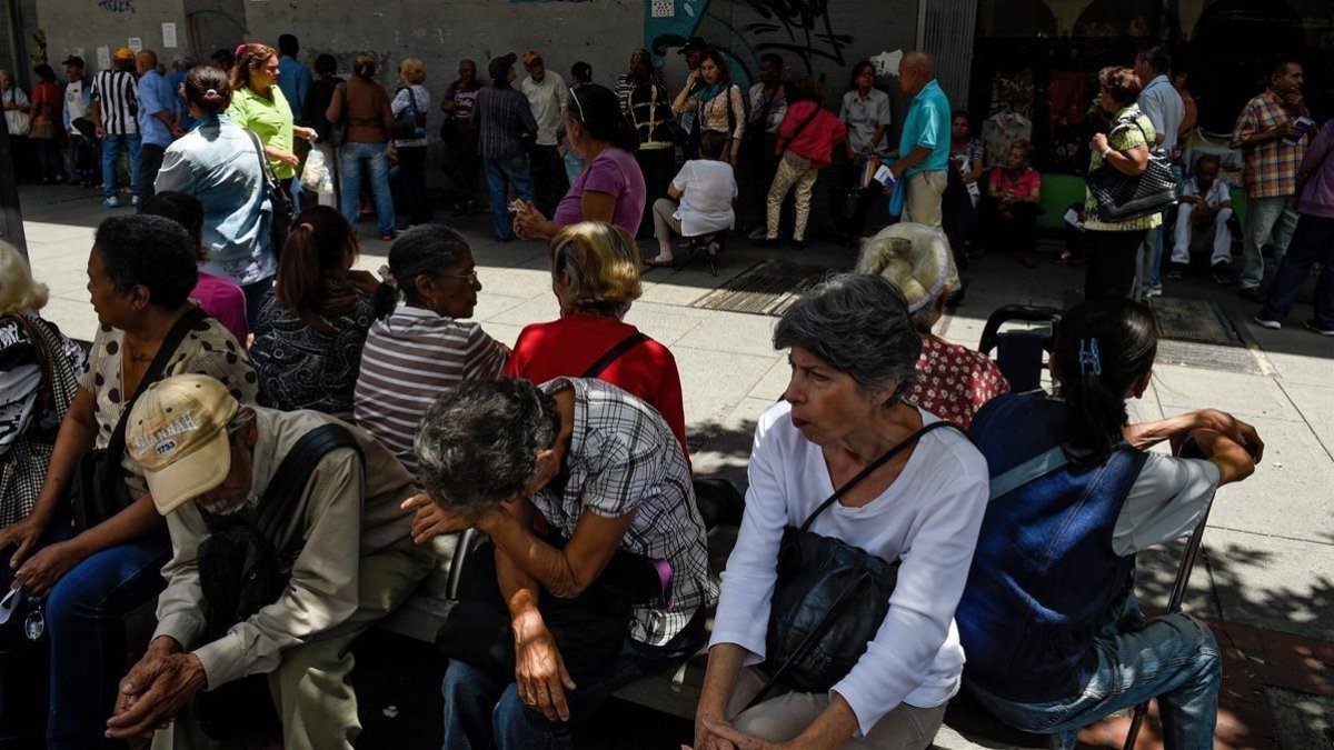 Un grupo de venezolanos hacen cola frente a un banco de Caracas para cobrar sus pensiones.-FEDERICO PARRA