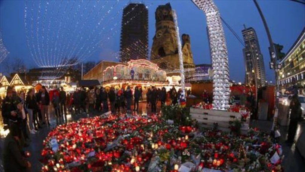 Altar de flores y velas en el mercadillo navideño de Berlín, que ayer reabrió.-AP / MARCUS SCHREIBER