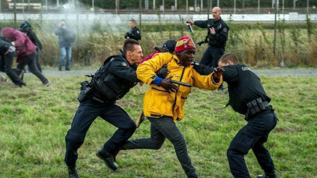 Policías franceses intentan parar a los inmigrantes que buscan colarse al Eurotúnel en Calais este miércoles.-AFP/PHILIPPE HUGUEN