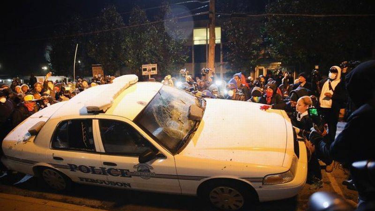 Vecinos de Ferguson golpean un coche de policía, el martes durante las protestas.-Foto: AFP / SCOTT OLSON