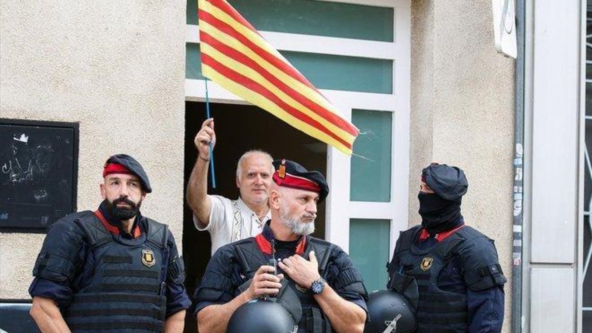 Un hombre con una ’senyera’, junto a unos agentes en la operación contra los CDR en Sabadell.-ANNA MAS