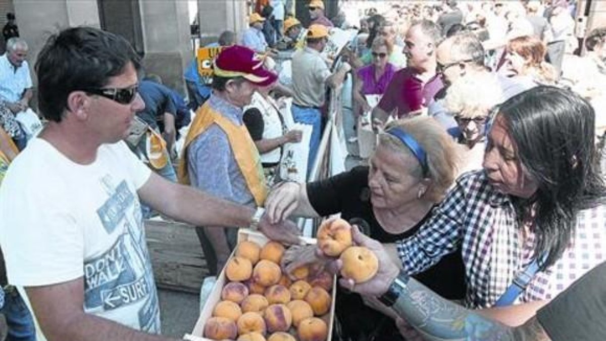 Agricultores reparten melocotones en una protesta del sector en Zaragoza.-EFE / TONI GALÁN