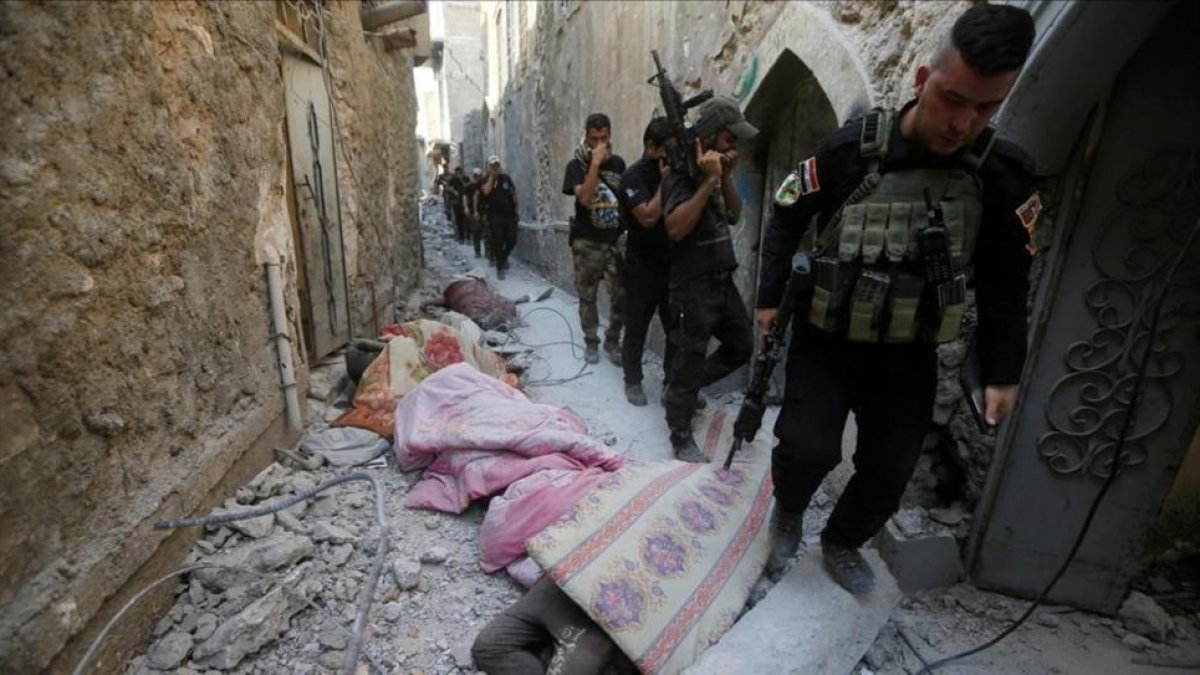 Miembros de los equipos antiterroristas iraquís pasan junto a cadáveres de combatientes del Estado Islámico en una calle de la ciudad vieja de Mosul.-ALAA AL-MARJANI / REUTERS