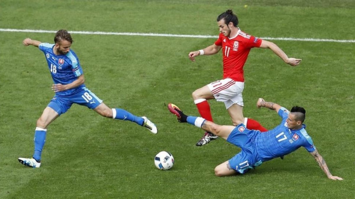 Bale conduce el balón perseguido por dos rivales en el partido inaugural de Gales.-HASSAN AMMAR / AP