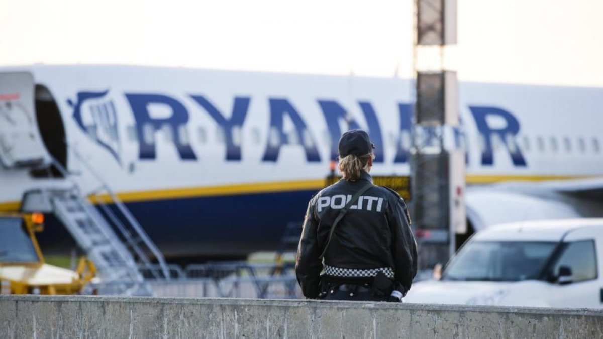 Un agente de policía, frente al avión de Ryanair evacuado, el domingo en el aeropuerto noruego de Moss-Rygge.-AP / HAAKON MOSVOLD