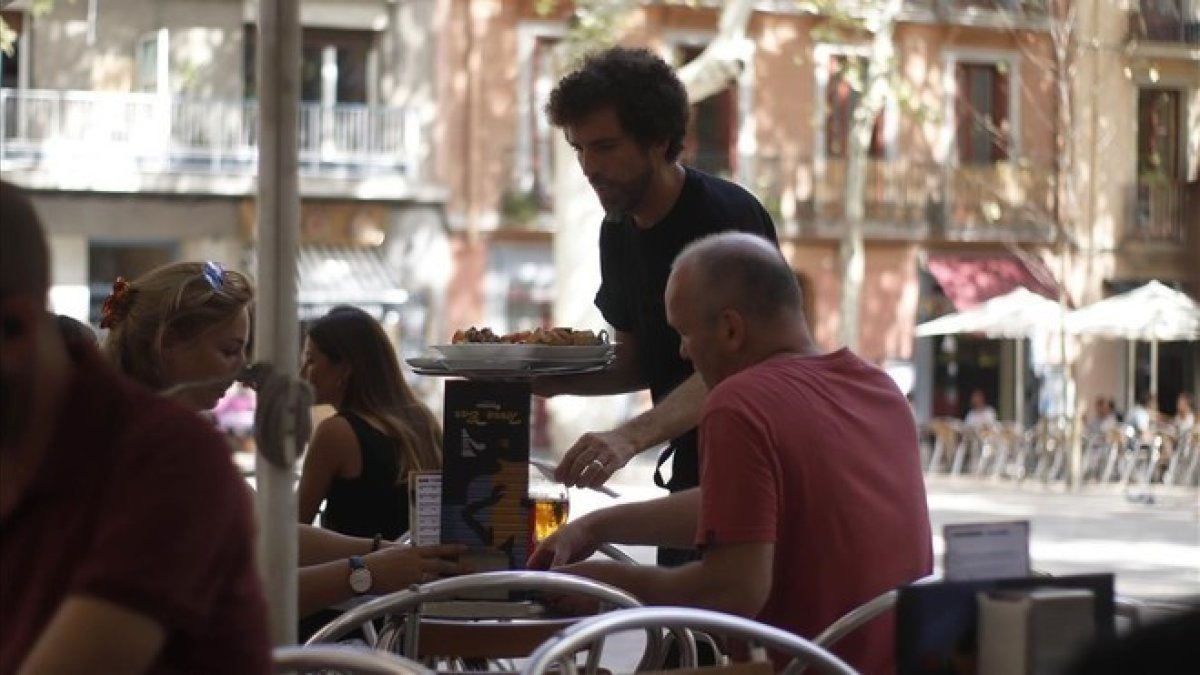 Un camarero atiende a unos clientes.-PAULA GONZÁLEZ