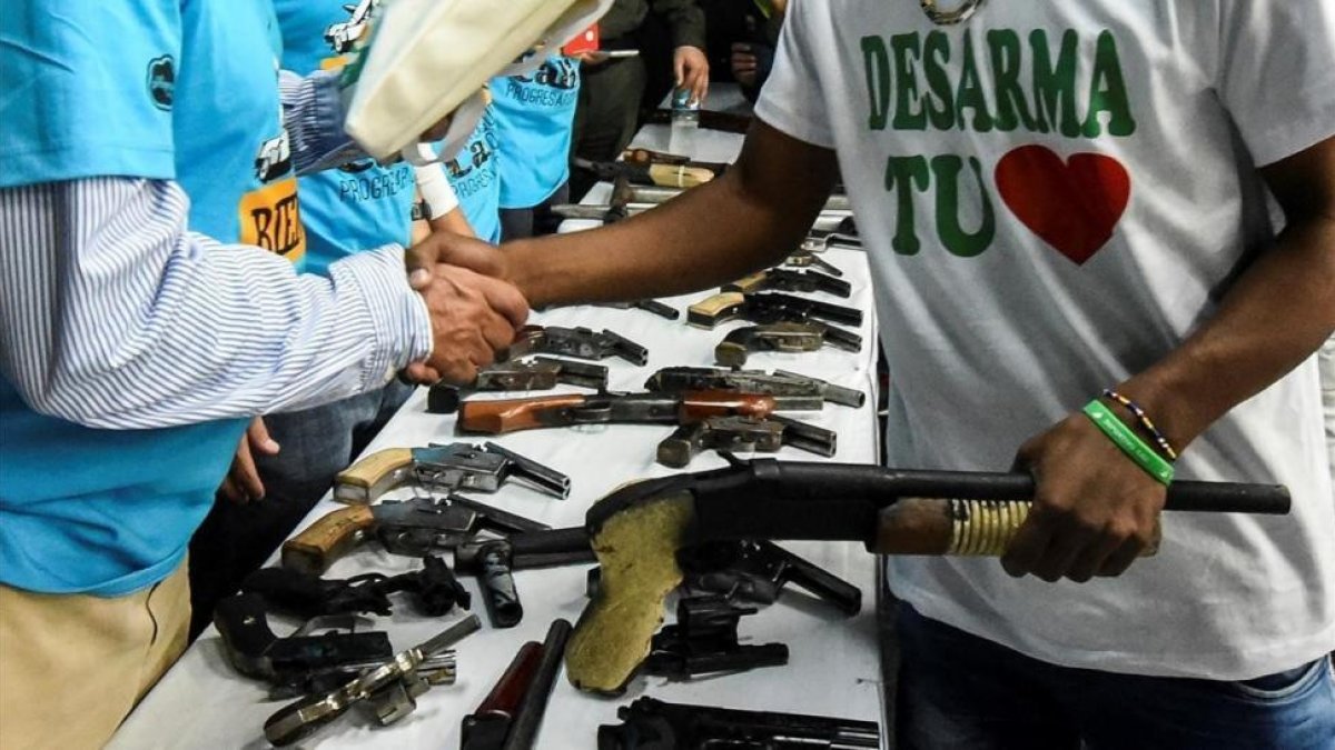 Un miembro de una banda entrega su arma en una ceremonia en Cali, el pasado julio-AFP / LUIS ROBAYO