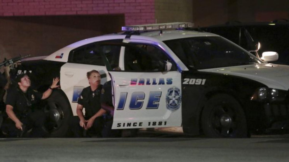 Varios policías, parapetados tras un coche patrulla, durante el tiroteo en Dallas.-Maria R. Olivas / AP