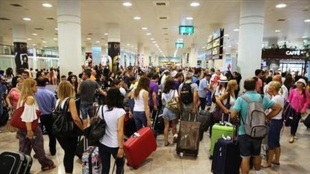 Decenas de pasajeros en el Aeropuerto del Prat.-RICARD CUGAT