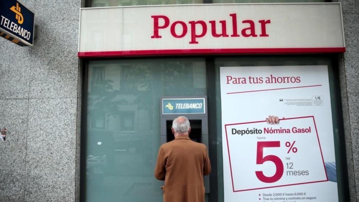 Un hombre saca dinero de un cajero del Popular en Madrid.-REUTERS / ANDREA COMAS