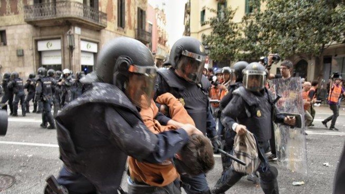 Dos policías con uno de los manifestantes detenidos en Via Laietana.-MANU MITRU